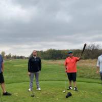 Four alumni posing together on golf course